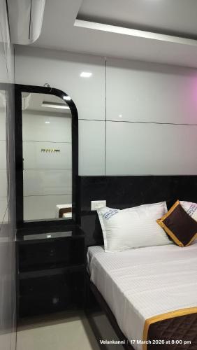 a bedroom with a bed with a black headboard and a mirror at Hotel Grand Arputha in Velankanni