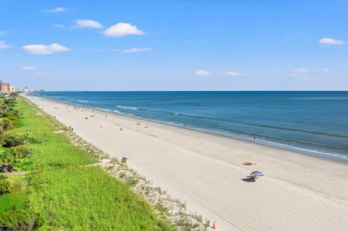a beach with people on it and the ocean at Oceanfront 3BR with Stunning Views, Private Balcony and Pool in Myrtle Beach