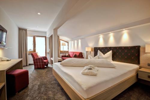 a bedroom with a large white bed and red chairs at Hotel Gemma - Adults only in Hirschegg