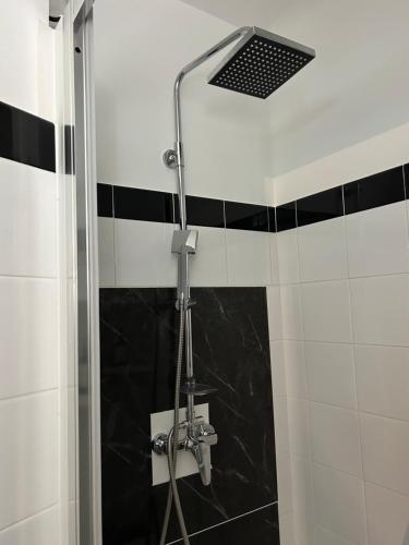 a shower in a bathroom with black and white tiles at Appartement charmant au cœur de Saint-Rémy, idéal pour une escapade provençale ! in Saint-Rémy-de-Provence