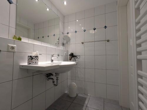 a white bathroom with a sink and a mirror at Suite Hotel Villa Erika in Borkum