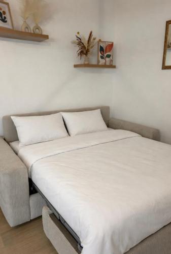 a bed with white sheets and a couch in a room at Appartement charmant au cœur de Saint-Rémy, idéal pour une escapade provençale ! in Saint-Rémy-de-Provence