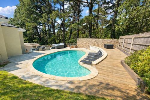 a swimming pool with chairs and a wooden deck at 5 Bed House - Pool - Hot Tub - Sauna - Pool Table - Near New Forest and Beach - Sleeps 12 in Ringwood