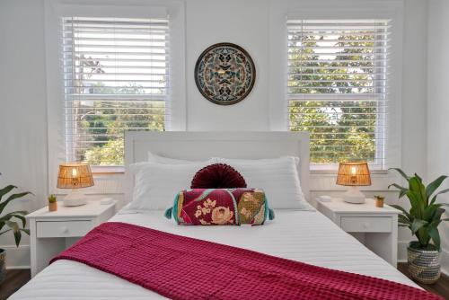 a bedroom with a white bed and two windows at Urban Oasis in Wilmington