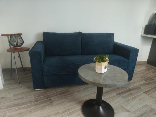 a living room with a blue couch and a table at Chez Olga studio indépendant in Giberville