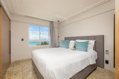 a bedroom with a large white bed with blue pillows at Coral Plaza Apart Hotel in Natal
