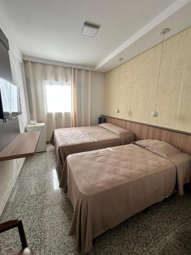 a hotel room with two beds and a television at Ancona Center Hotel in Amparo