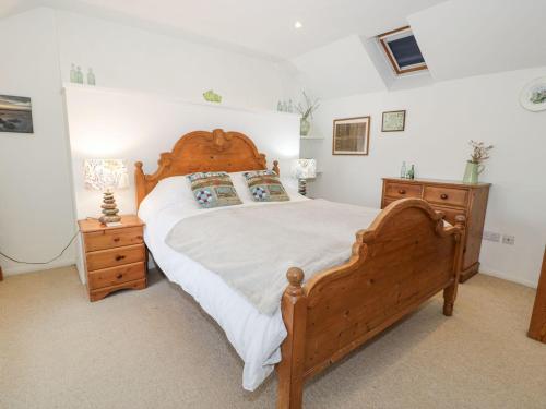 a bedroom with a wooden bed and a wooden dresser at Happy Landing in Harlech