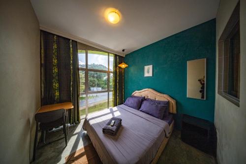 a bedroom with a bed with blue walls and a window at The Cottage Stay - self check-in in Kuching