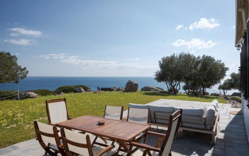 a wooden table and chairs with a view of the ocean at My Way Kavos Villa in Agia Marina Aegina