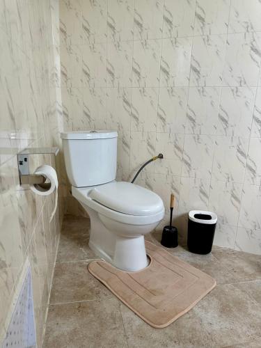 a white toilet in a bathroom with a rug at Nahé Résidence Deux Plateaux in Abidjan