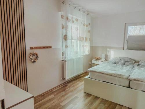 a white bedroom with a bed and a window at Ferienhaus "Schmale Gisela" bis zu 6 Personen mit Garten und Parkplätzen in Seligenstadt