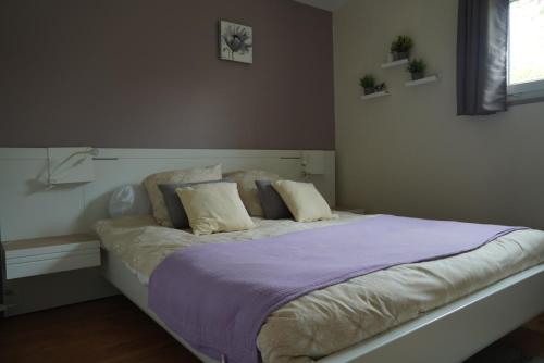 a bedroom with a bed with purple sheets and pillows at Maison individuelle in Triac-Lautrait