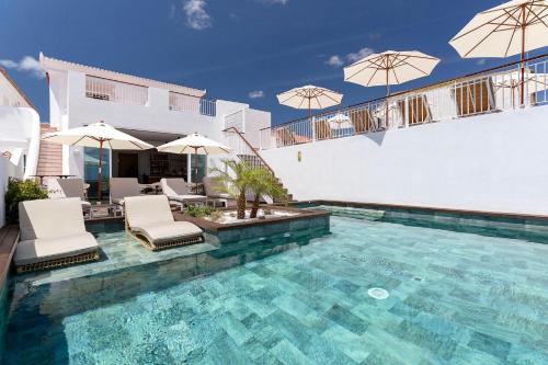 a swimming pool with chairs and umbrellas on a house at Água Hotels Lagos Bay in Lagos