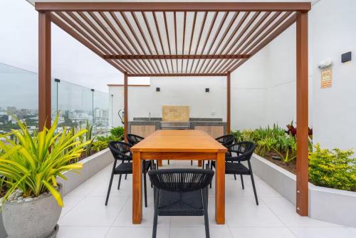 a wooden table and chairs on a balcony with plants at Ejército City Lofts & Apartments by Geko in Lima