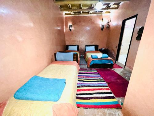a room with three beds and a rug at riad imlil in Imlil