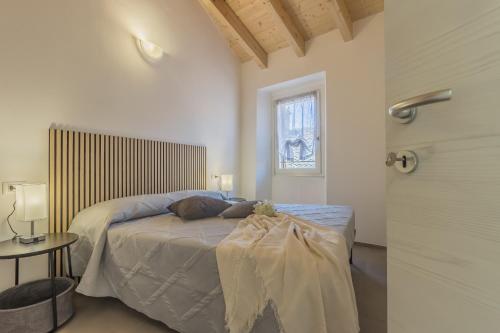 a white bedroom with a bed and a window at Ca Magnolia Appartamento 4 in Lierna