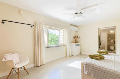 a white bedroom with a bed and a white chair at Villa Kas Karibense 38 - Coral Estate in Willibrordus