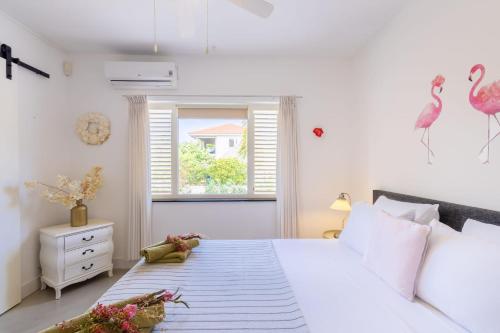a bedroom with a large white bed with pink flamingos on the wall at Villa Kas Karibense 38 - Coral Estate in Willibrordus