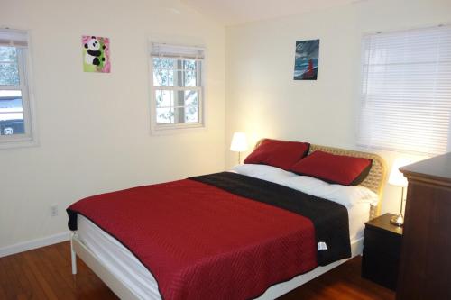 a bedroom with a bed with a red blanket and two windows at Mountain home in Newland in Newland