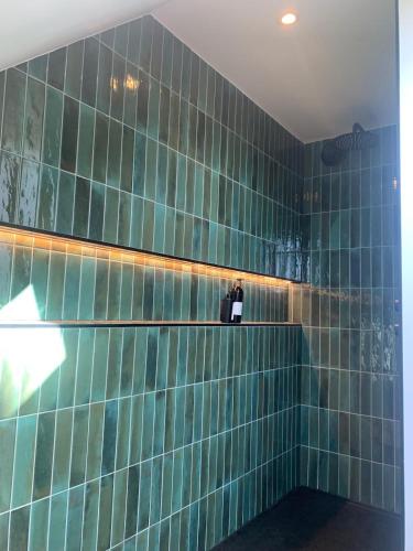 a bathroom with green tiles on the wall at Vakantiewoning Vaib in Kortemark