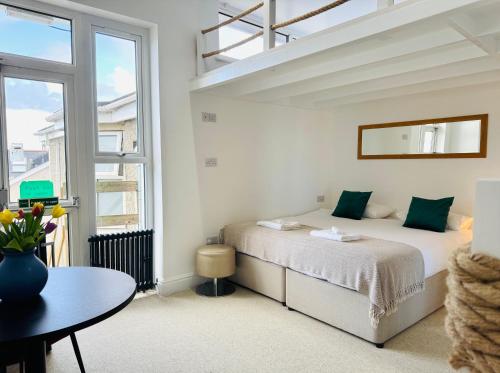 a white bedroom with a bed and a table at Reef Lodge in Newquay