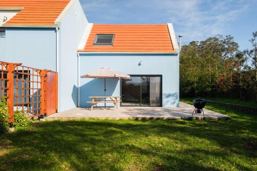 an orange roofed house with a picnic table and a grill at FishTail Guest House in Rabo de Peixe