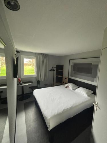 a bedroom with a large white bed and a desk at Hotel ibis Autun in Autun