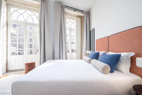 a bedroom with a large white bed with blue pillows at Aspasios Trindade Apartments in Porto