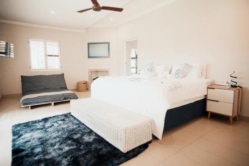 a bedroom with a white bed and a chair and a rug at Megs Guesthouse in Ballito
