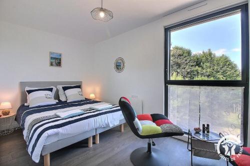 a bedroom with a bed and a chair and a window at ô nid des grèves in Langueux