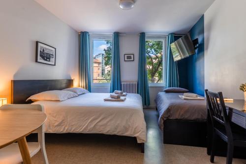 two beds in a room with two windows at Blue Bird - Logement sur les Ramblas in Toulouse