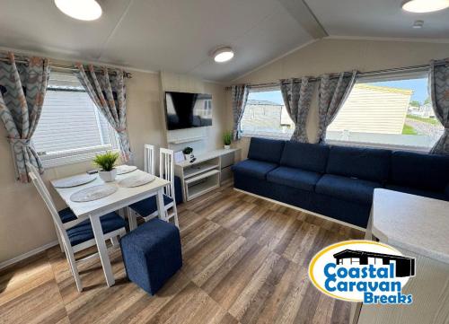 a living room with a blue couch and a table at Fantasy Island Resort - The Pearl F10, with Hot Tub - Coastal Caravan Breaks in Ingoldmells