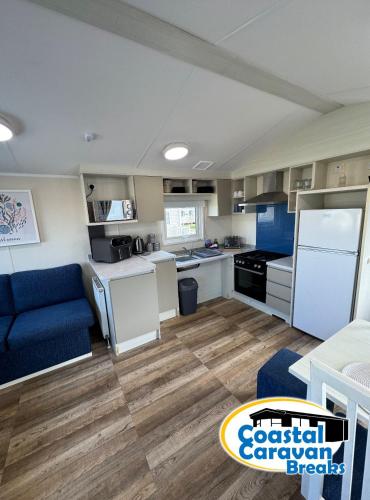 a kitchen with white appliances and a blue couch at Fantasy Island Resort - The Pearl F10, with Hot Tub - Coastal Caravan Breaks in Ingoldmells