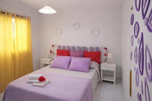 a bedroom with a large bed with purple and red pillows at Sunny Pool Apartment Costa del Silencio in Arona