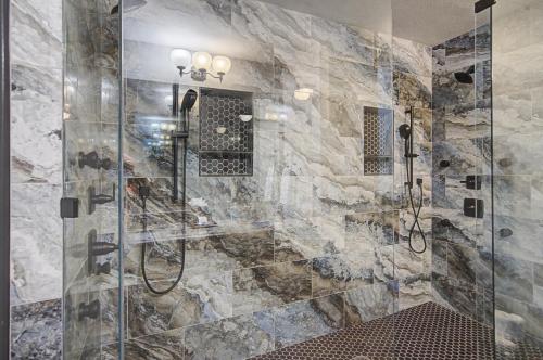 a bathroom with a walk in shower next to a stone wall at Shop & Dine: Fort Worth Condo w/ Racetrack Views! in Fort Worth