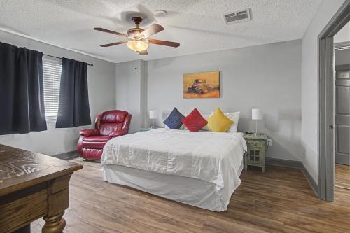 a bedroom with a bed with a ceiling fan and a chair at Shop & Dine: Fort Worth Condo w/ Racetrack Views! in Fort Worth