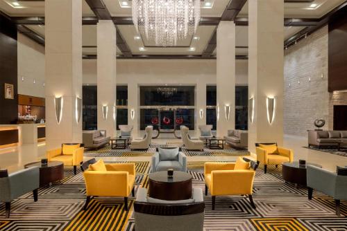 a lobby with chairs and tables and a chandelier at Radisson Blu Hotel, Dubai Barsha Heights in Dubai