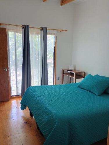 ein Schlafzimmer mit einem Bett mit grüner Bettdecke in der Unterkunft Cabaña Peralillo in Vicuña