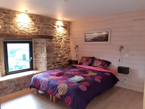 a bedroom with a bed and a stone wall at Gîte coup de cœur in Pluvigner