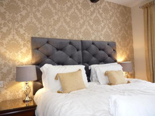 a bedroom with a large bed with white sheets and pillows at The Old Seven Stars in Okehampton