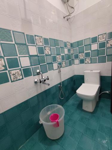 a green and white bathroom with a toilet and a bucket at Hotel Rhythms Residency in Chennai