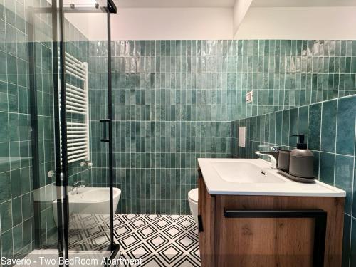 a green tiled bathroom with a sink and a shower at Saverio & Daria Aprtements by Mamo Florence in Florence