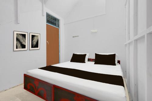 a bedroom with a large white bed with black pillows at SPOT ON Milan Hotel in Hāthras