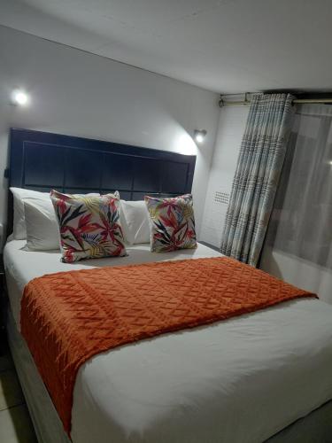 a bedroom with a large bed with an orange blanket at Carravensiria Chalet 27 in Hibberdene