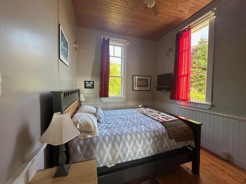 a bedroom with a bed and two windows at Trinity's Oceanview Gem 2BR St Paul's Schoolhouse in Trinity