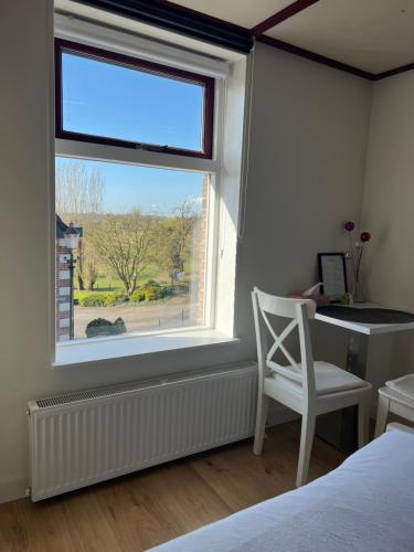 a bedroom with a window with a desk and a chair at Rustig verblijf bij de Rijn - Lobith in Lobith