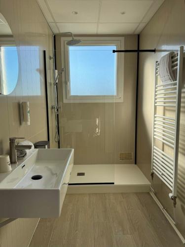 a bathroom with a large white sink and a window at Cit'Hôtel l'Europe - Cholet Gare in Cholet