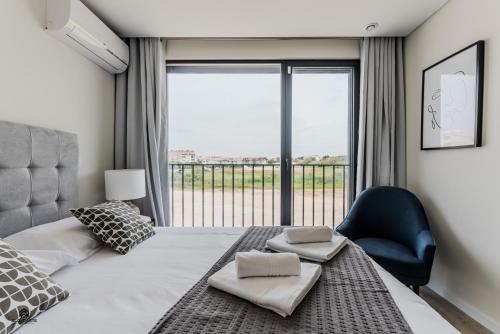 a bedroom with a bed and a chair and a large window at Shore Apartments - Santa Cruz in Santa Cruz