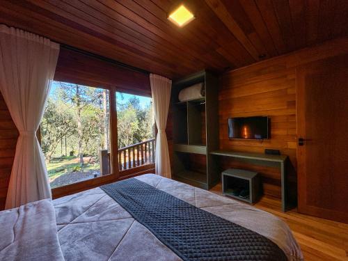 a bedroom with a bed and a tv and a window at Villa Vida Cabanas in São Joaquim